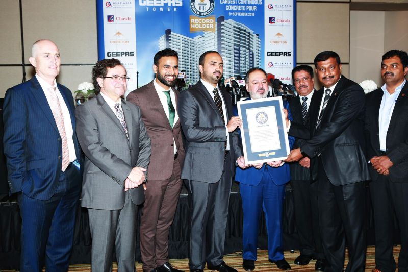 Przedstawiciele Gulf Asia Contracting i Geepas z certyfikatem Guinnessa przed banerem Geepas Tower