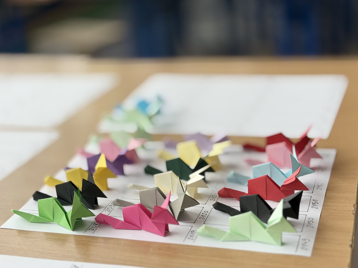 Kolorowe lisy origami ustawione na ponumerowanej kartce A4