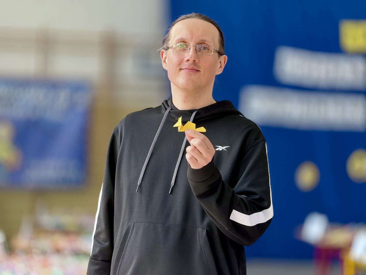 Łukasz Pietruszka, rekordzista Guinnessa, z żółtym lisem origami na tle wystawy w Piszu